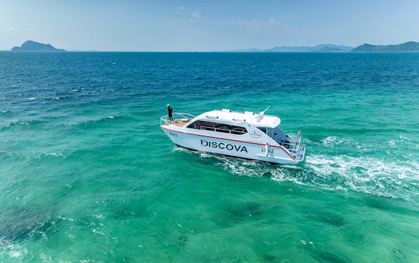 Speedboat cruising in Phang Nga Bay, Thailand with distant islands.