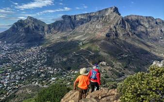 Hikers descending Lion's Head with Table Mountain view in Cape Town.