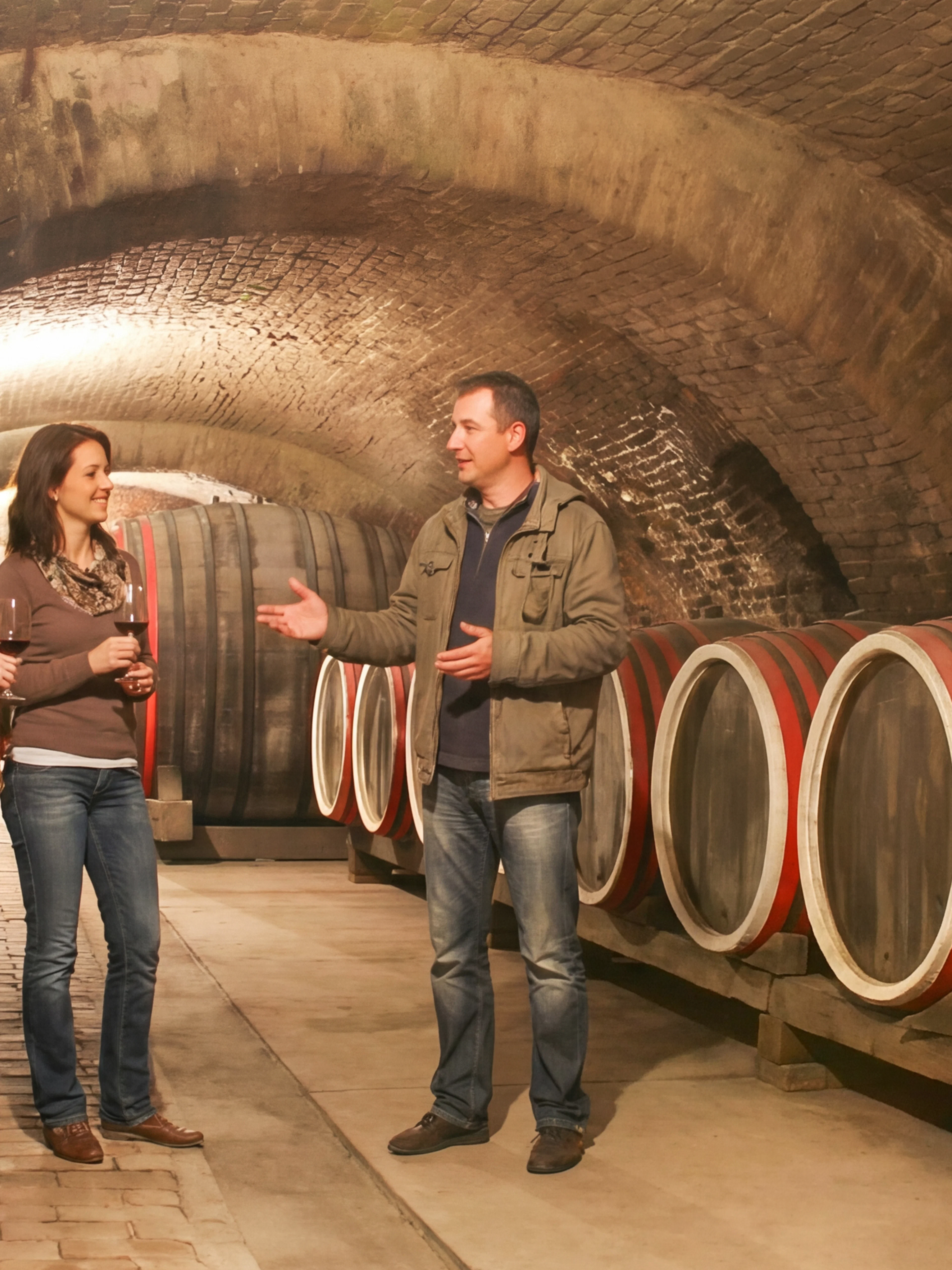 Tour group in an old wine cellar with large wooden barrels.