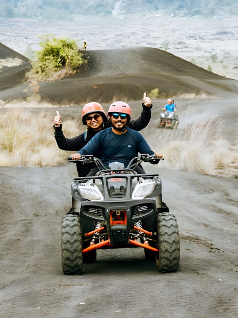 ATV riders on a dirt trail in Kintamani with Mount Batur in the background.