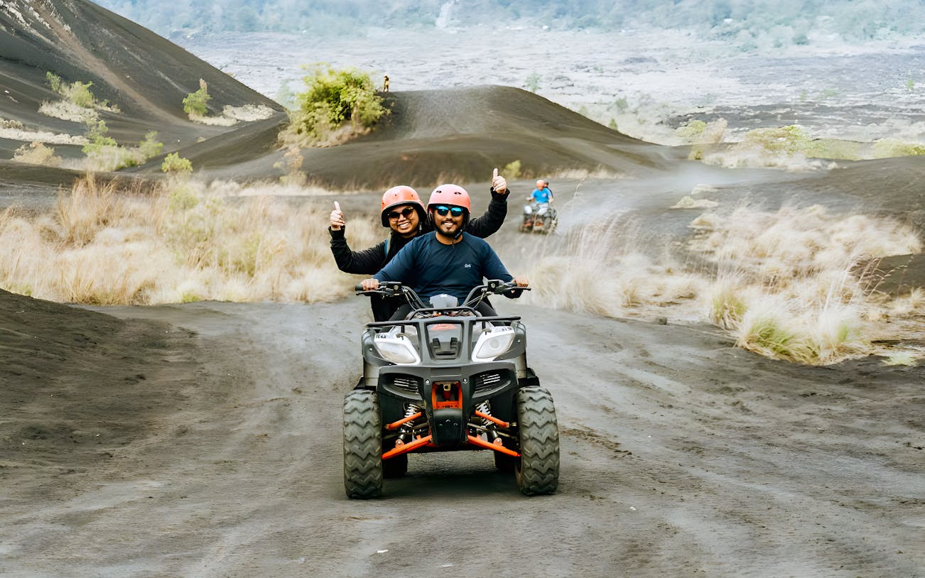 ATV riders on a dirt trail in Kintamani with Mount Batur in the background.