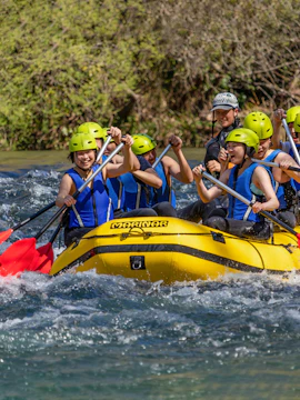 Group rafting on Cetina River in yellow raft with helmets and paddles.