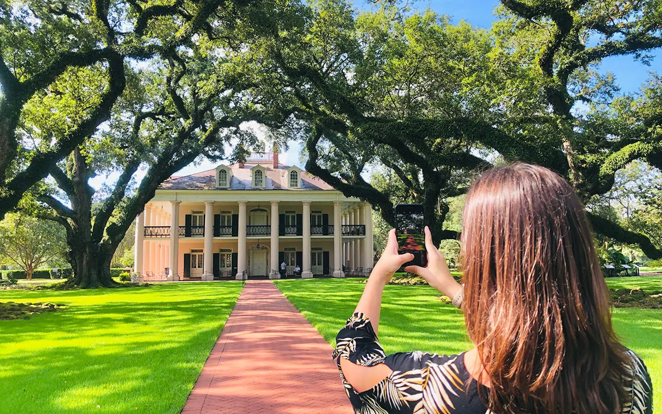 Visitor photographing Oak Alley Plantation's grand entrance, New Orleans tour.