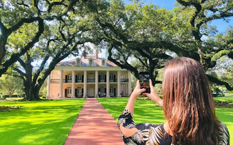 Visitor photographing Oak Alley Plantation's grand entrance, New Orleans tour.