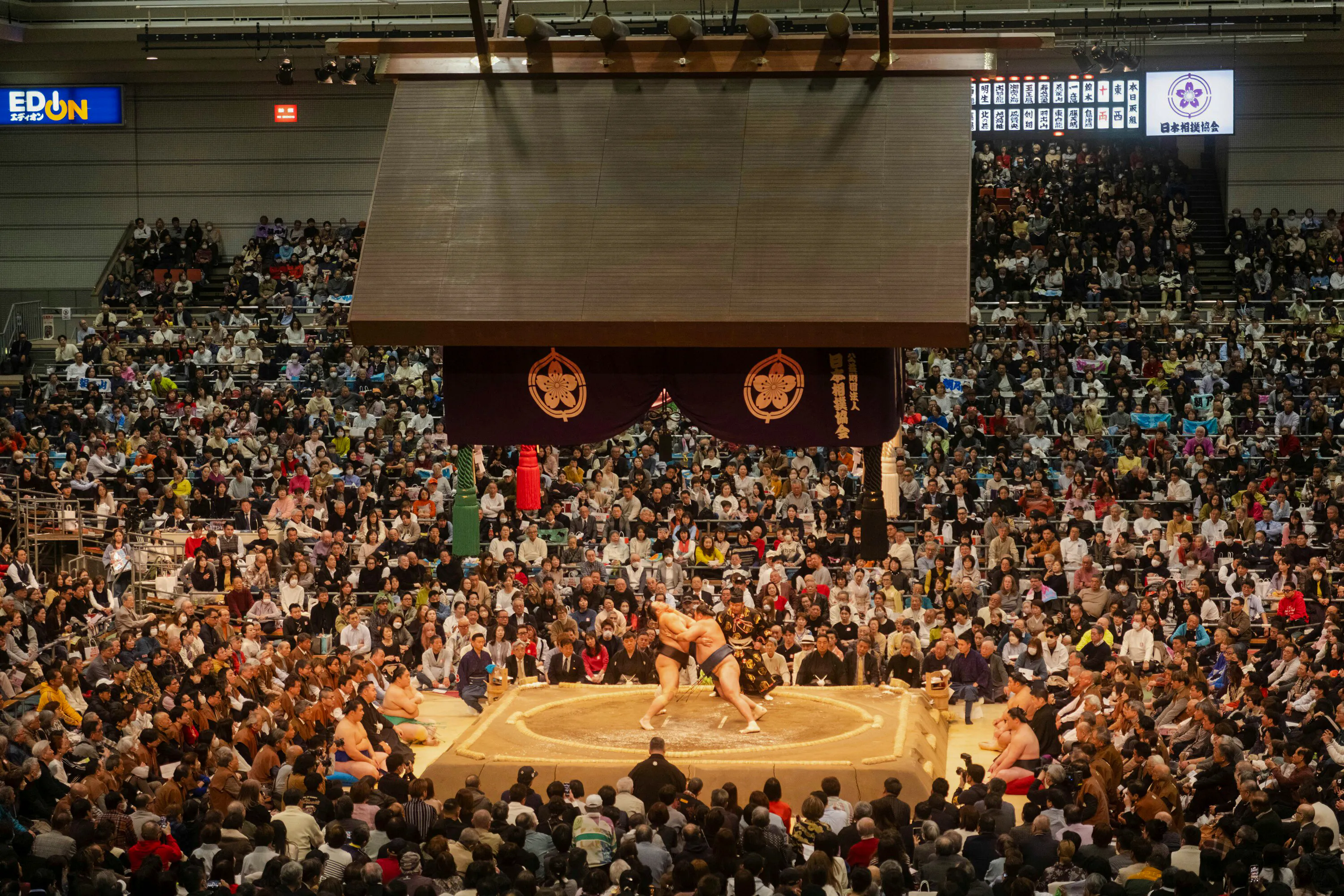 Sumo wrestlers competing in the Nagoya Grand Sumo Tournament with a large audience.