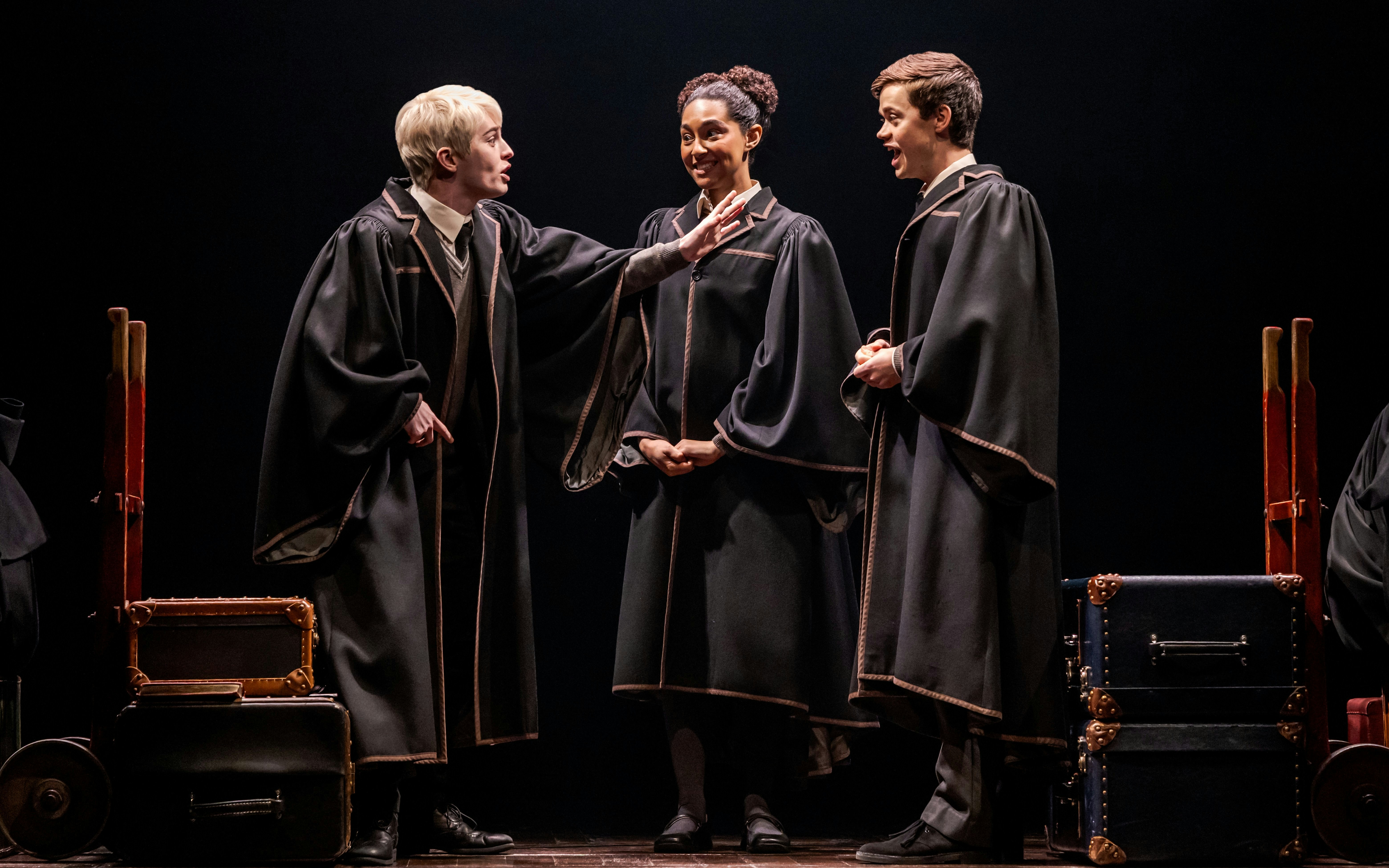 Actors in wizard robes performing "Harry Potter and the Cursed Child" on Broadway stage.