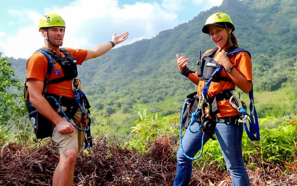 Zipline guides at Kualoa Ranch, Hawaii, with lush mountain backdrop.