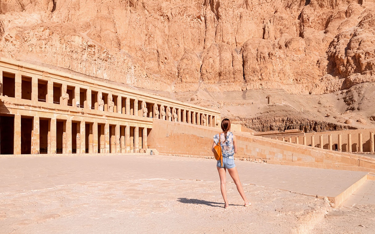 Tourist admiring Hatshepsut Temple's ancient architecture in Luxor, Egypt.