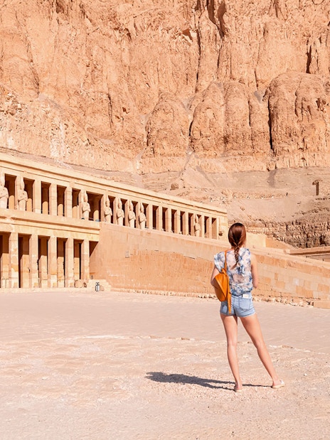 Tourist admiring Hatshepsut Temple's ancient architecture in Luxor, Egypt.