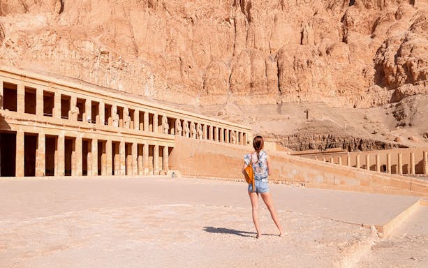 Tourist admiring Hatshepsut Temple's ancient architecture in Luxor, Egypt.