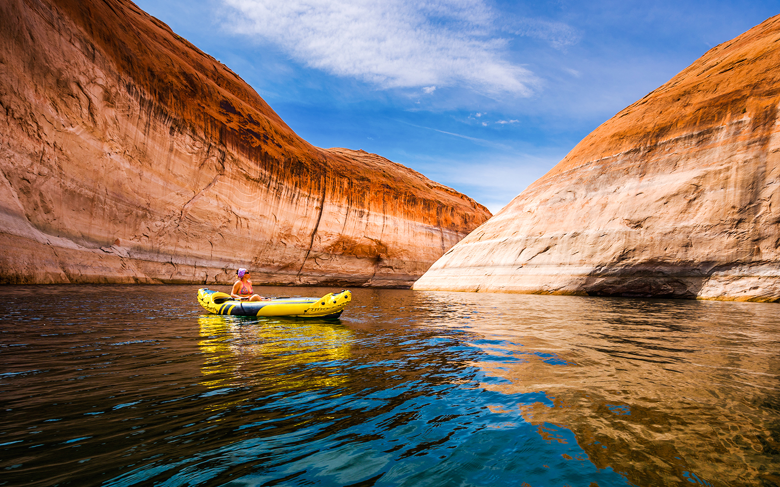 Kayaker paddling through narrow canyon walls on Lake Powell, Arizona.