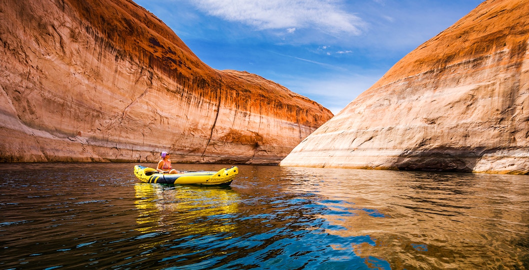 Kayaker paddling through narrow canyon walls on Lake Powell, Arizona.