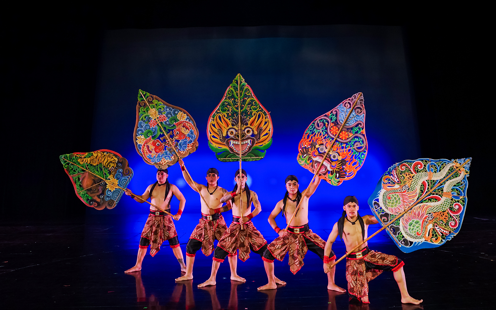 Performers at Devdan Show in Bali holding colorful shields, showcasing Indonesian dance.