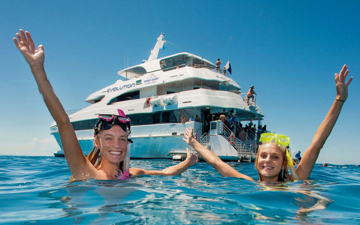 Snorkelers enjoying the water near a cruise ship on a Cairns to Great Barrier Reef tour.