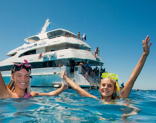 Snorkelers enjoying the water near a cruise ship on a Cairns to Great Barrier Reef tour.