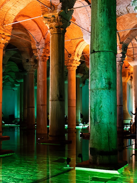 Illuminated columns inside Basilica Cistern, Istanbul, reflecting on water.