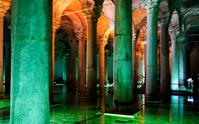 Illuminated columns inside Basilica Cistern, Istanbul, reflecting on water.