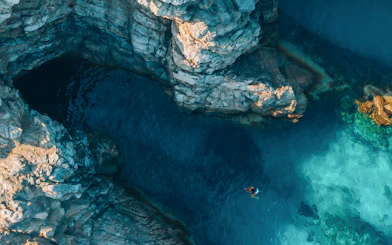 Swimmer near rocky cliffs and clear waters of Blue Cave, Dubrovnik.