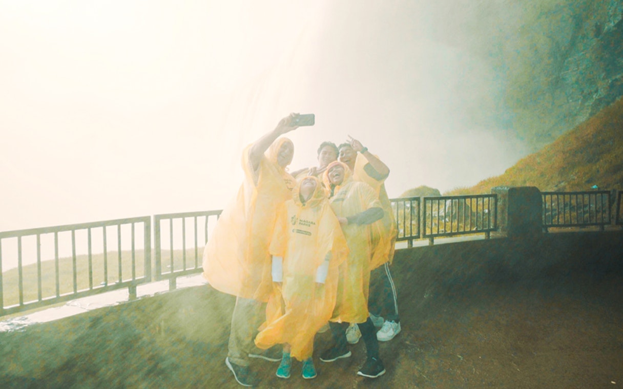Visitors in yellow ponchos taking a selfie at Journey Behind the Falls, Niagara Falls.