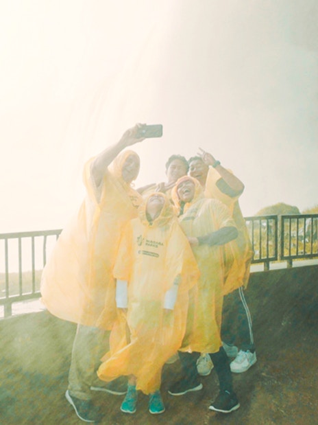 Visitors in yellow ponchos taking a selfie at Journey Behind the Falls, Niagara Falls.