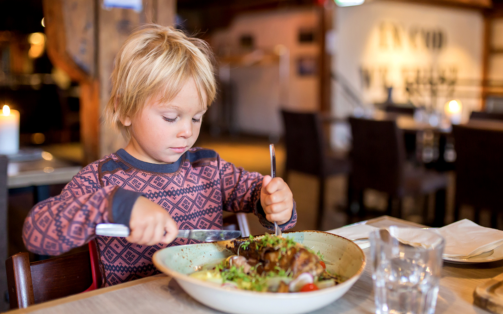 Child enjoying a meal in a cozy Arctic restaurant during Fjord Expedition.