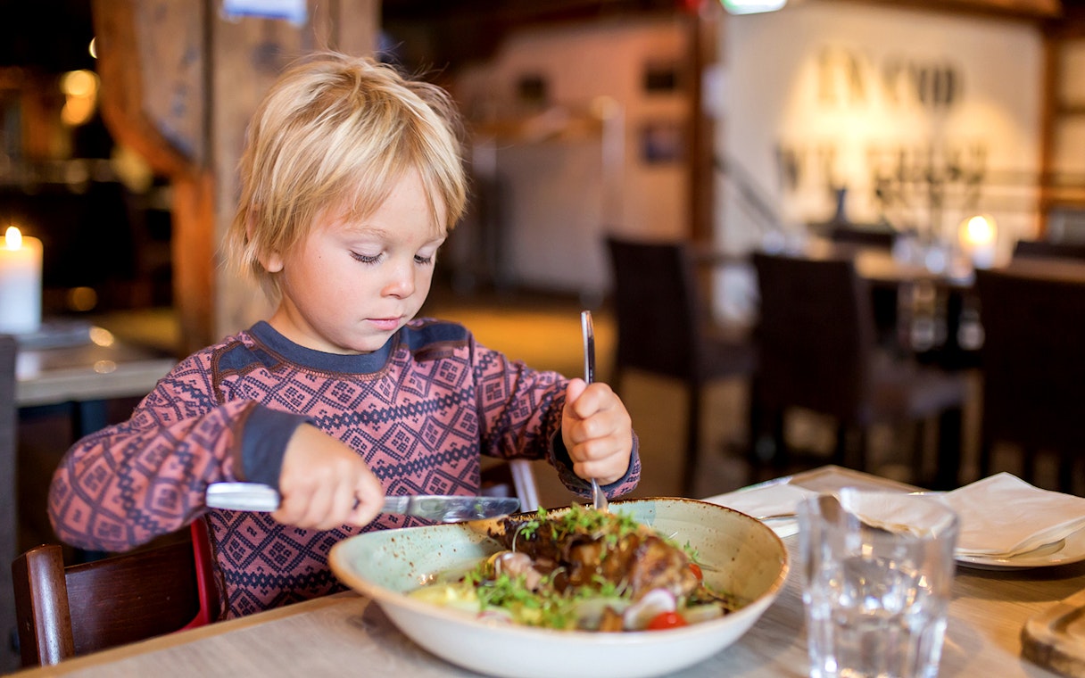 Child enjoying a meal in a cozy Arctic restaurant during Fjord Expedition.
