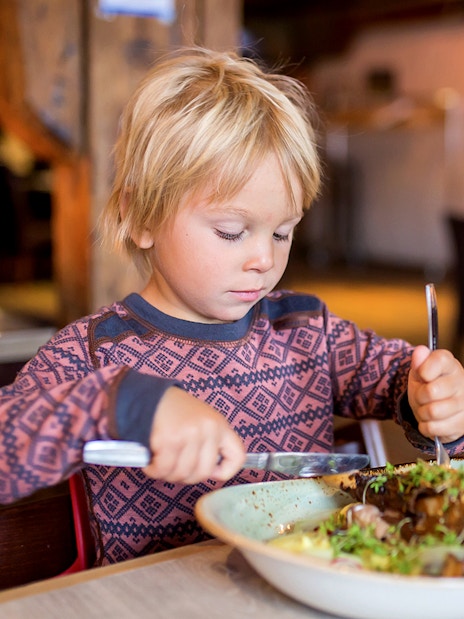 Child enjoying a meal in a cozy Arctic restaurant during Fjord Expedition.