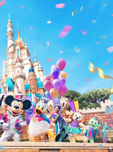 Disney characters celebrating 20th anniversary at Hong Kong Disneyland with castle backdrop.