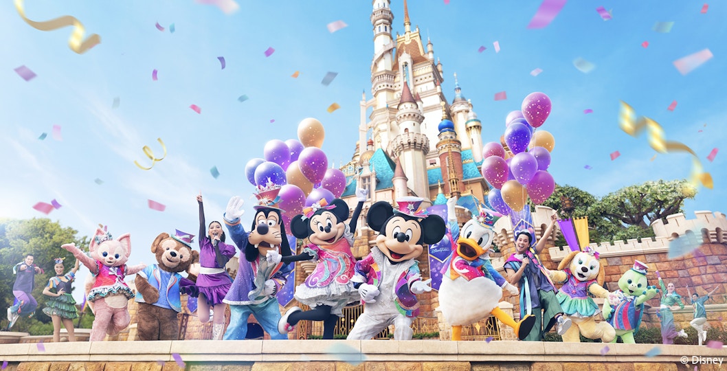 Disney characters celebrating 20th anniversary at Hong Kong Disneyland with castle backdrop.