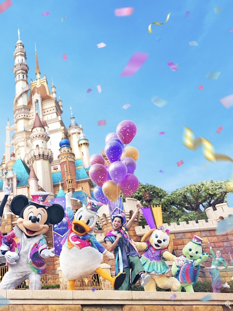 Disney characters celebrating 20th anniversary at Hong Kong Disneyland with castle backdrop.