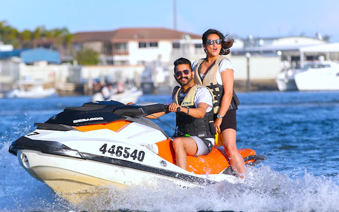 Jet skiing adventure with two people on a vibrant watercraft near a marina.
