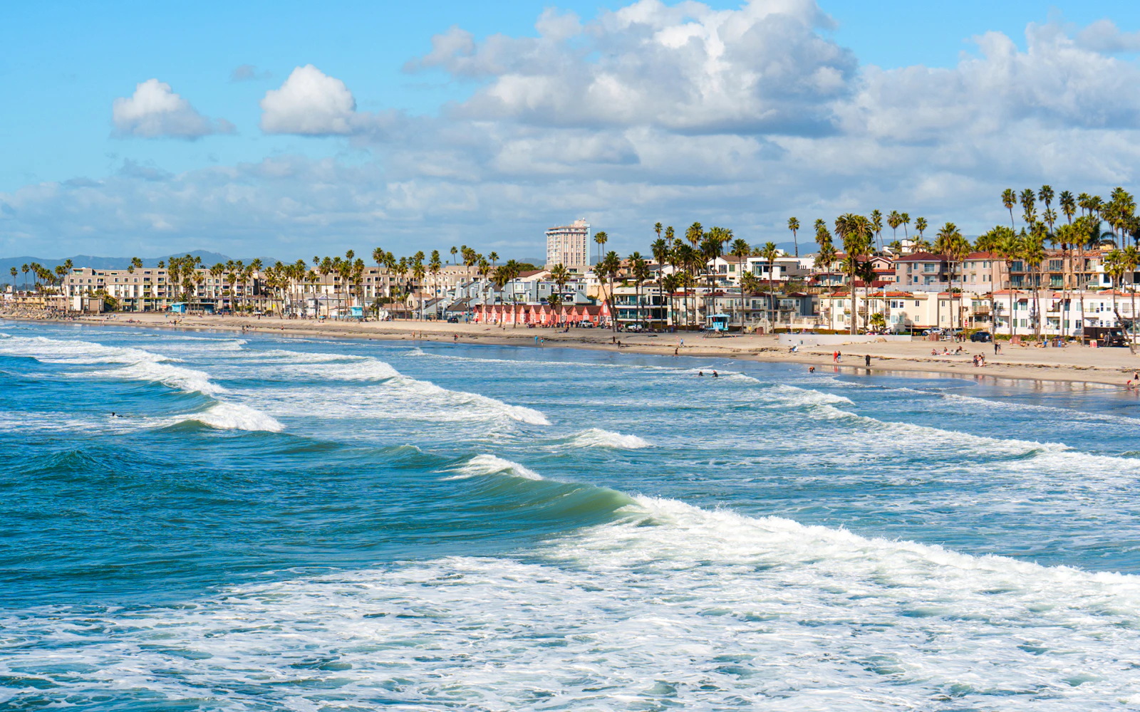 Oceanside Beach coastline with waves and palm trees, California.