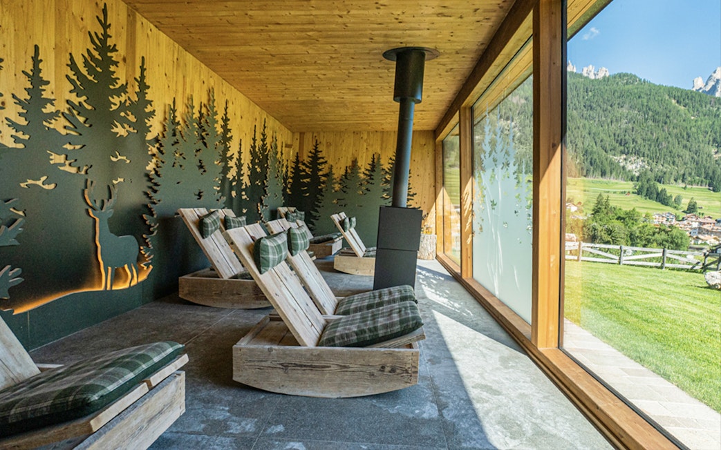 Lounge chairs in a relaxation room at QC Terme Resort & Spa, Dolomiti, with forest view.