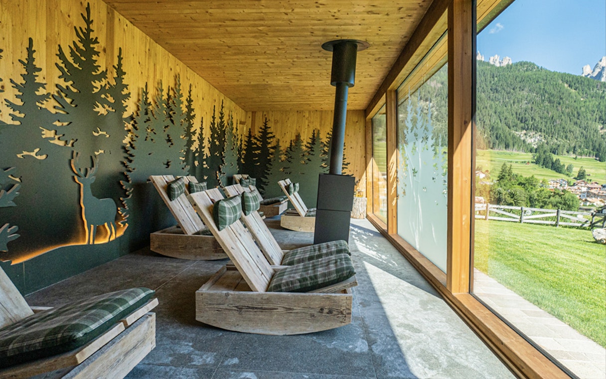 Lounge chairs in a relaxation room at QC Terme Resort & Spa, Dolomiti, with forest view.