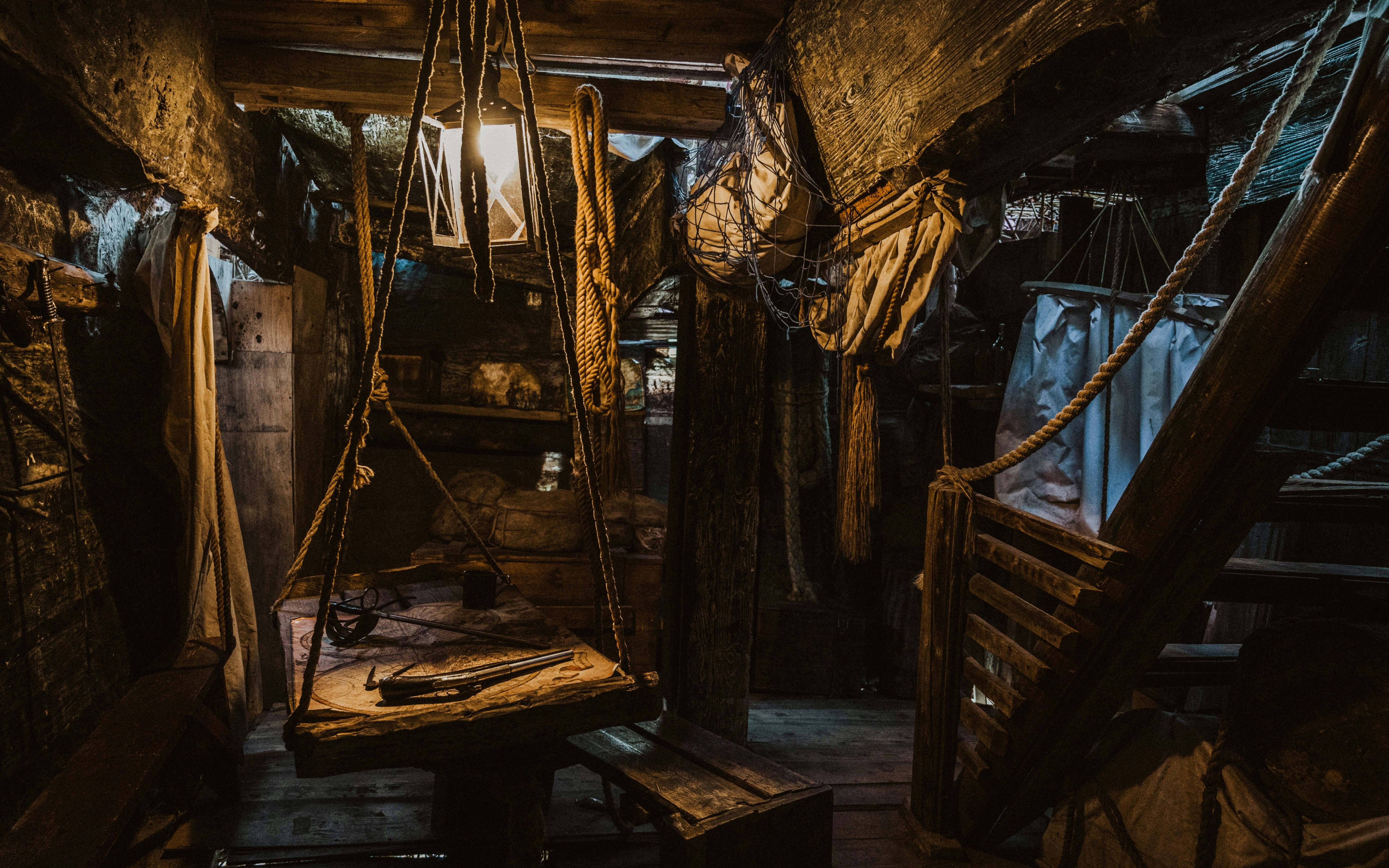 Pirate ship captain's cabin interior with ropes, wooden table, and lantern.