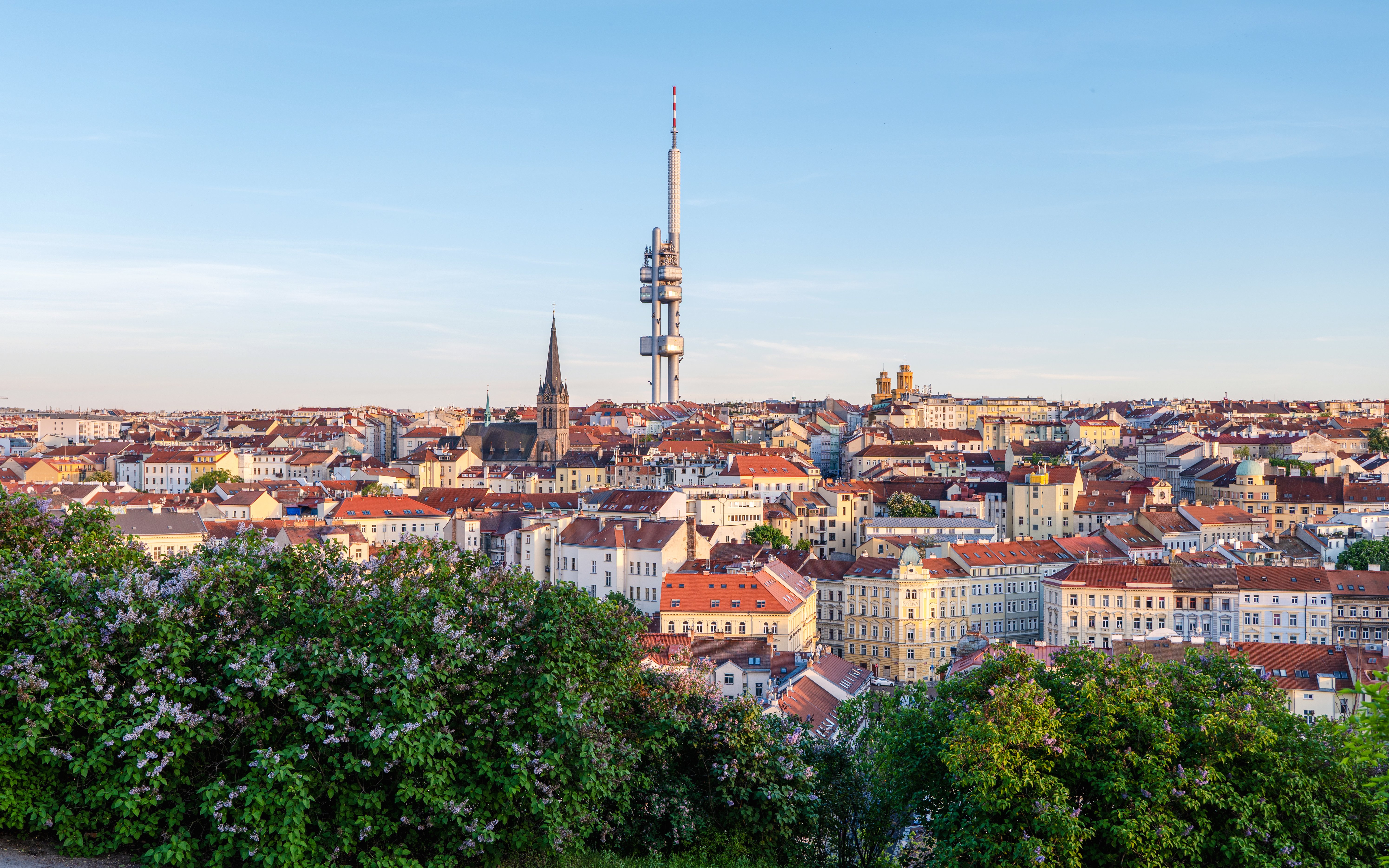 Zizkov TV Tower rising above Prague's cityscape with historic buildings.