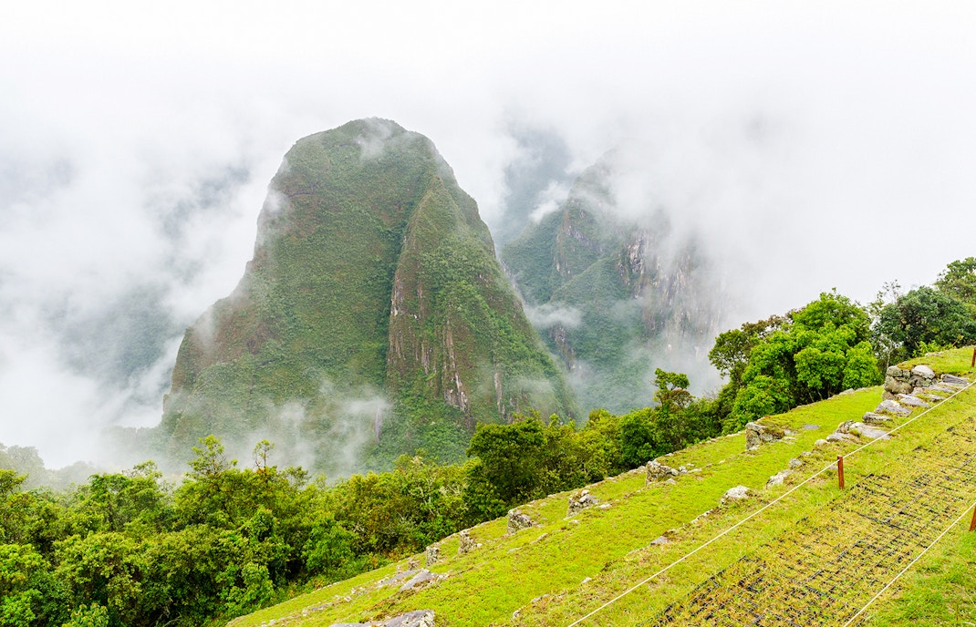 Putucusi mountain and Machu Picchu's terraces shrouded in mist, Peru.