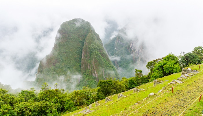 Putucusi mountain and Machu Picchu's terraces shrouded in mist, Peru.