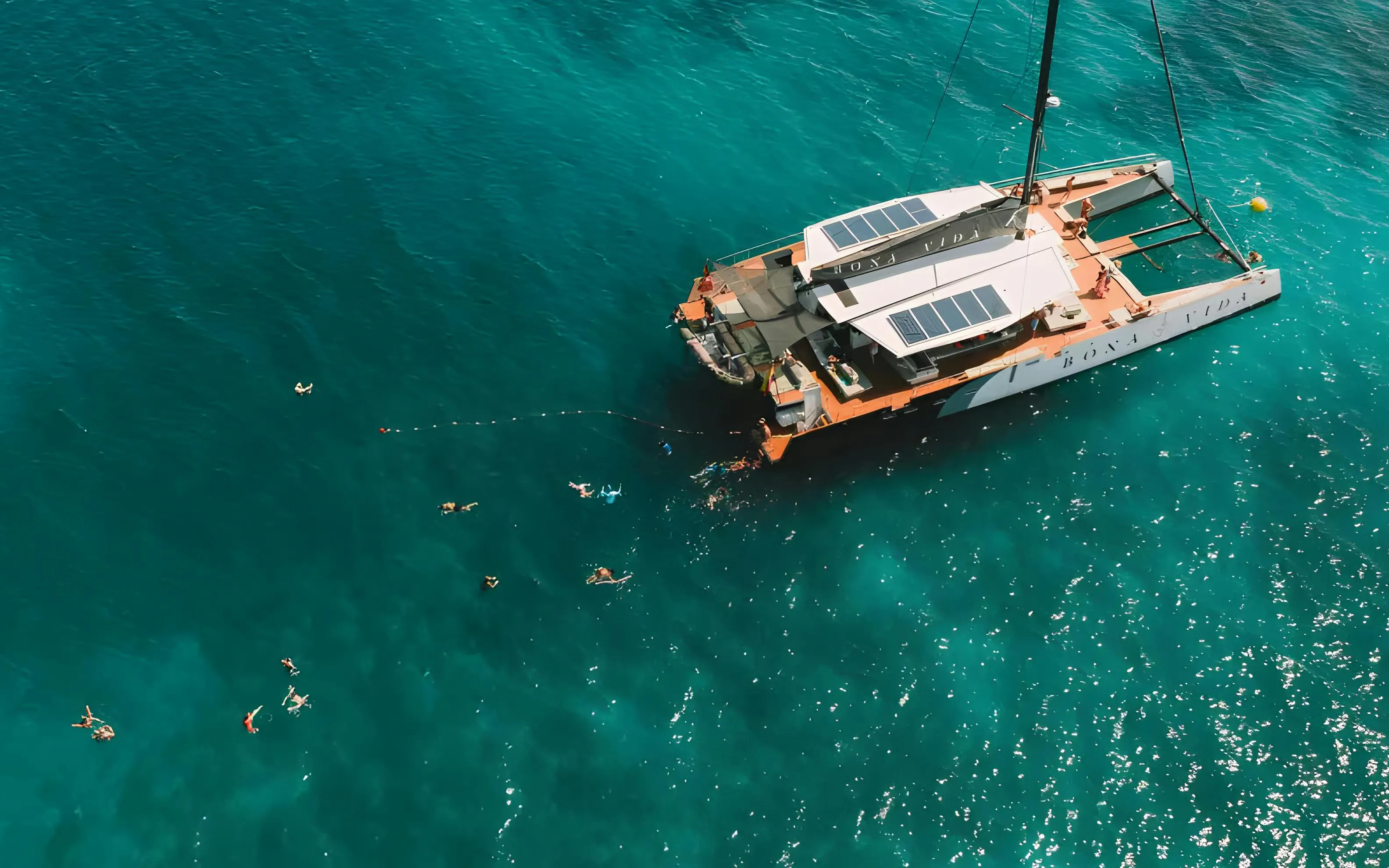 Catamaran with swimmers in clear waters during Rosario Islands cruise.