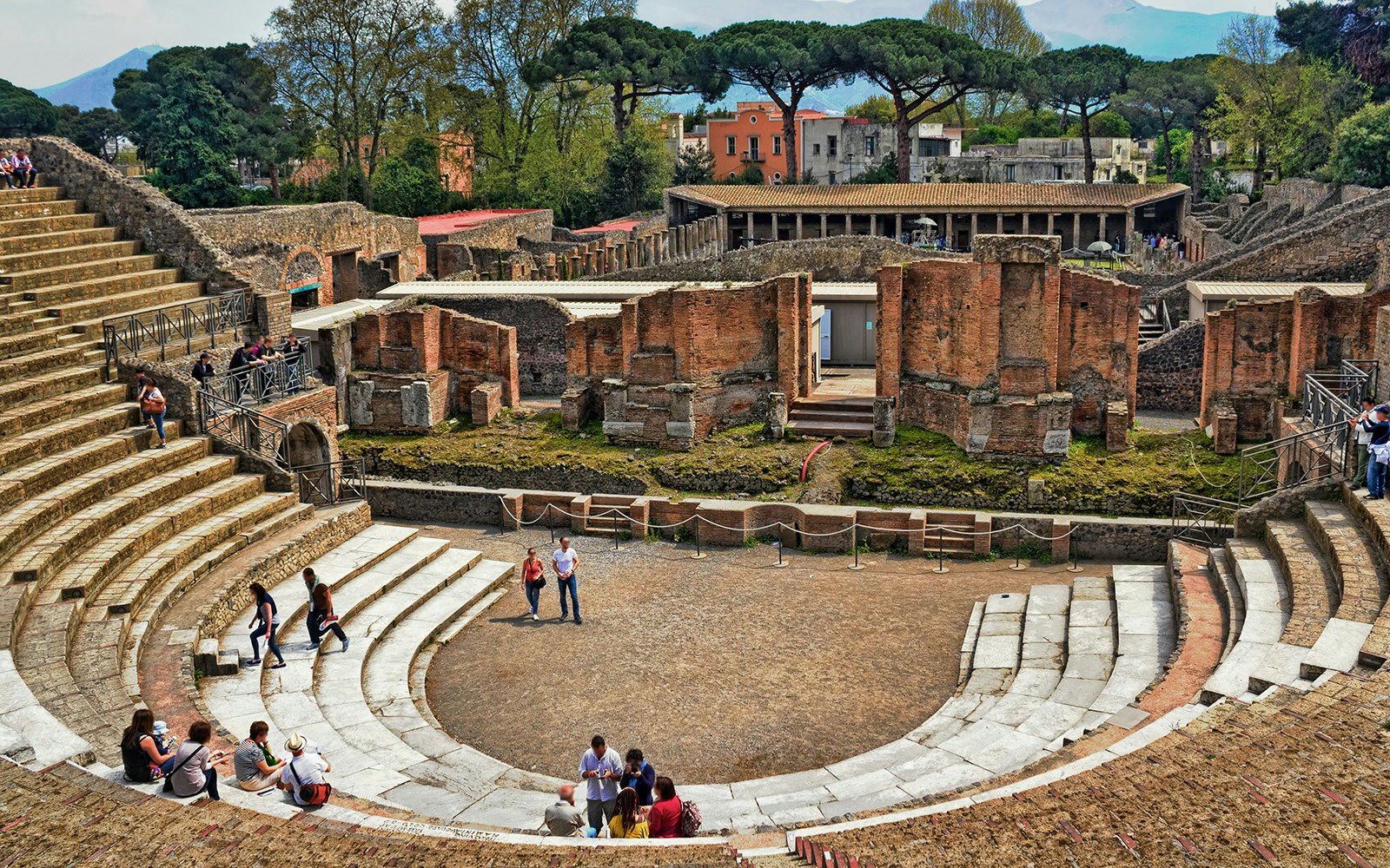 Ancient amphitheater in Pompeii with visitors exploring the ruins, Gulf of Naples.