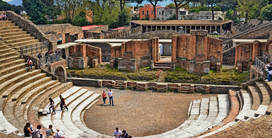 Ancient amphitheater in Pompeii with visitors exploring the ruins, Gulf of Naples.