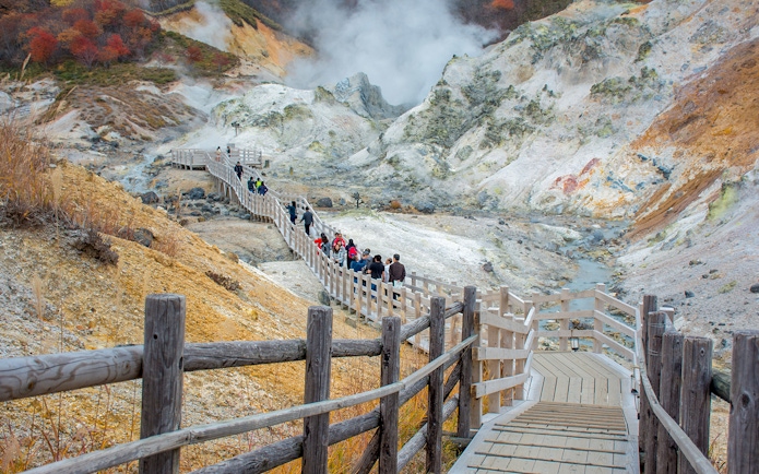 Visitors walking on a wooden path through Hell Valley in Noboribetsu, Japan.