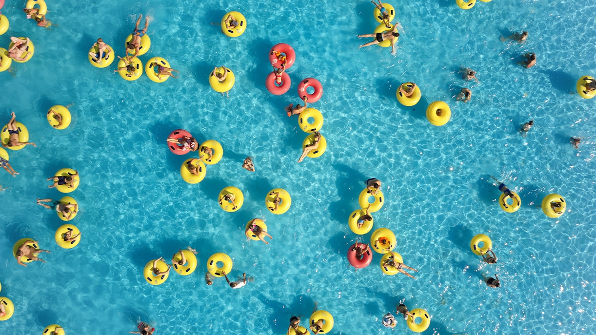People enjoying water activities on yellow and red floats at Yadi Yas Beach, Yas Waterworld.