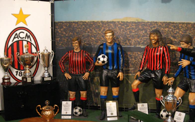 San Siro museum display with AC Milan memorabilia and player statues in Milan.