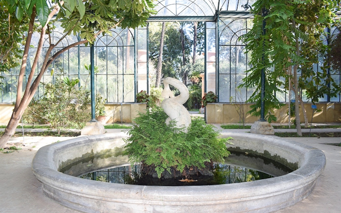 Sculpture in greenhouse at Orto Botanico, Palermo, surrounded by lush greenery.
