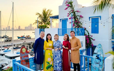 Group enjoying sunset at Son Tra Marina, Da Nang, with colorful buildings and boats in the background.