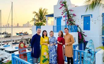 Group enjoying sunset at Son Tra Marina, Da Nang, with colorful buildings and boats in the background.