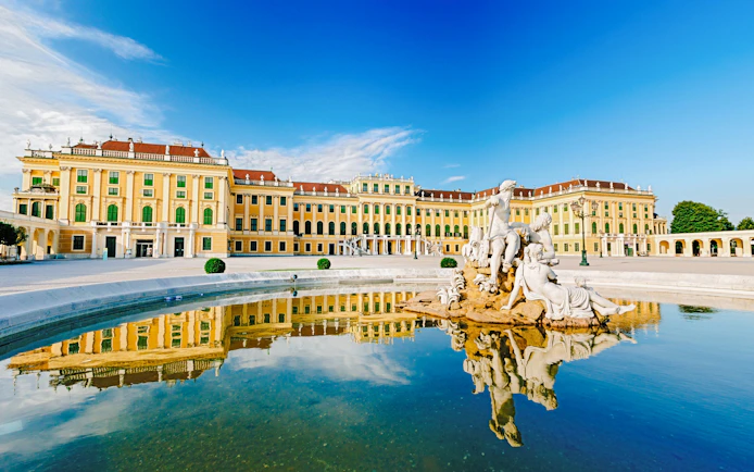 Schonbrunn Palace in Vienna with Neptune Fountain reflecting in the foreground.