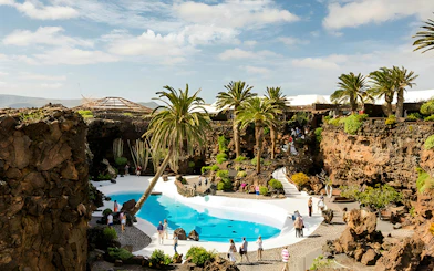 Jameos del Agua volcanic cave with palm trees and turquoise pool in Lanzarote.