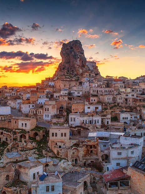 Cappadocia townscape at sunset with rock formations and mosque, Turkey.